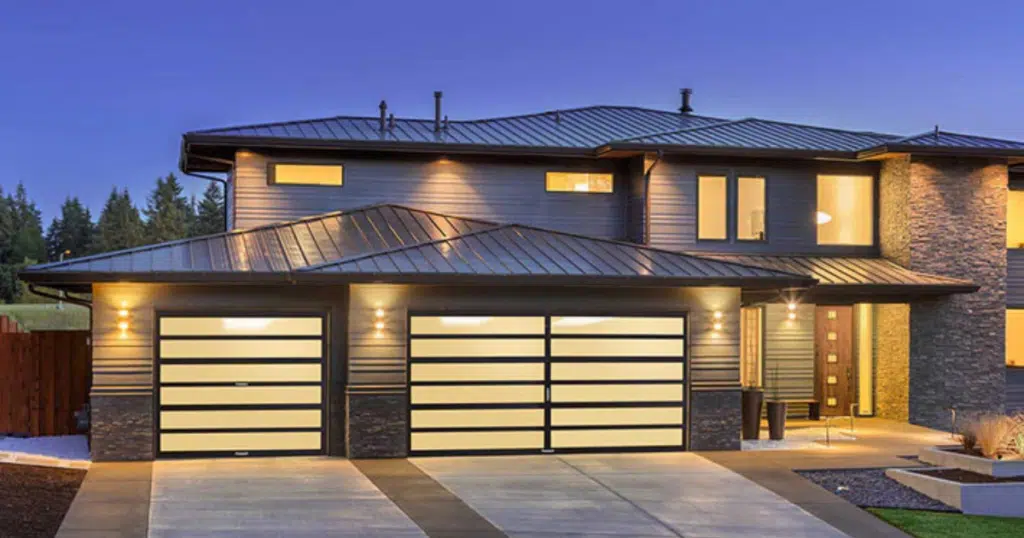 Modern house with illuminated glass garage doors.