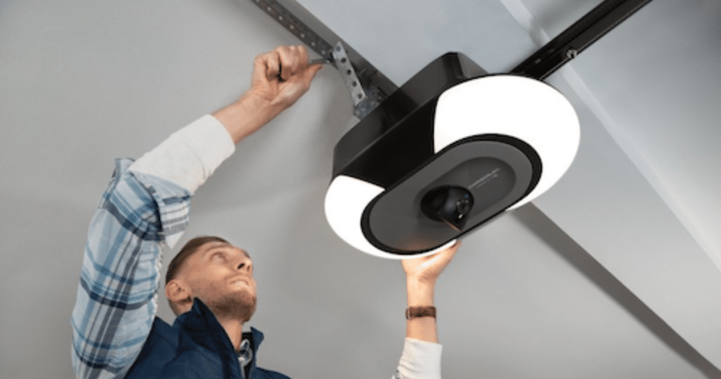 Man installs garage opener to ceiling bracket.
